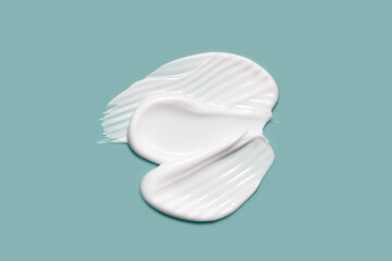 Skin care cream, lotion swatch smear on blue background. White creamy cosmetic product smudge closeup