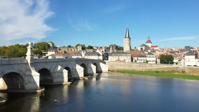 Scenic view of the historic stone bridge and old town architecture of La Charite sur Loire, France, under a clear blue sky.