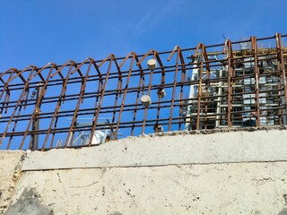 Construction worker tying deformed steel reinforcement bars with concrete cover blocks.