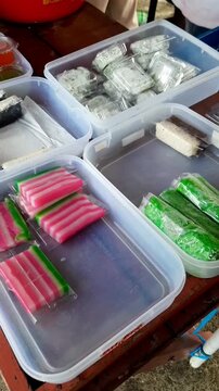 Various traditional Indonesian snacks in plastic packaging, including cake, jelly, pudding, and layered talam cake. street food. indonesia UMKM