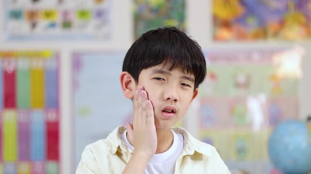 Asian School Boy Holding Cheek in Pain Due to Severe Toothache