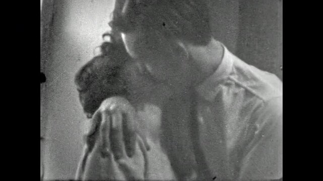 Old film, beautiful kiss between young couple indoors. Man holding woman in arms in long, sensual kiss. Romantic lovers together in happy affection relationship. Archival retro 1960s. Vintage archive