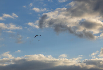 a motorized paraglider and an airplane against the backdrop of gray clouds