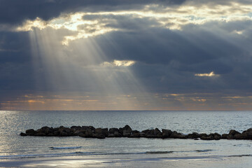 Beautiful sunset on the Mediterranean Sea with dark clouds and sun rays