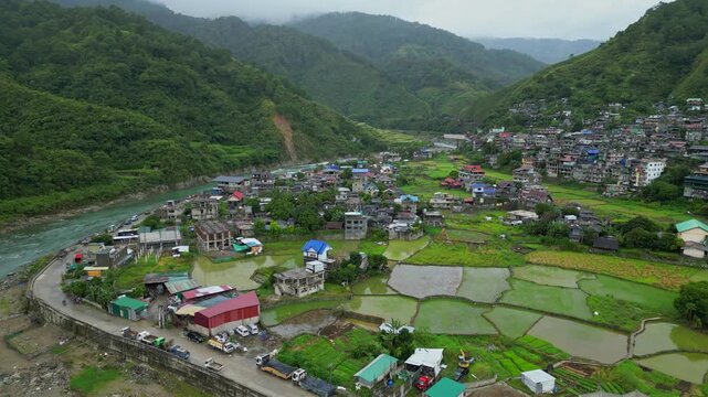 Overhead turning aerial focused on the residential clusters of Bontoc, Mountain Province, nestled along the winding banks of the surging Chico River, Ifugao Philippines.