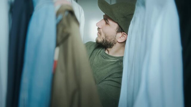 Young man urgently looking through wardrobe, appearing frustrated and indecisive while choosing an outfit, likely late or stressed.
