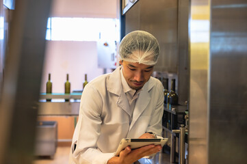 Male Japanese wine maker inspecting wine quality in fermenting room