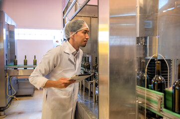 Male Japanese wine maker inspecting wine quality in fermenting room