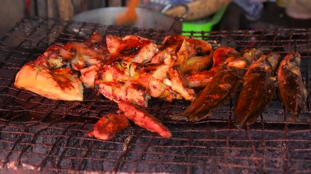 Close up view of cooking spicy Thai style chicken and fish. grilled on coal grill.