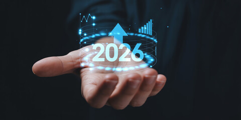 Hand holding futuristic glowing year 2026 with upward arrow graph future growth