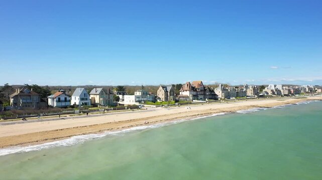 Aerial view of Sword Beach and seaside villas at Lion sur Mer, Normandy, France, on a clear sunny day. The image shows sandy beach, calm sea, and traditional French coastal architecture.
