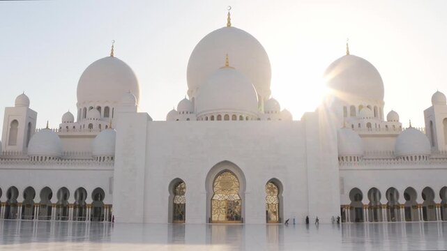 Tilt up view Abu Dhabi, UAE - Sheikh Zayed Mosque by Sunset. Sunflare soft lightning background. Visitor family sightseeing urban marvel of UAE