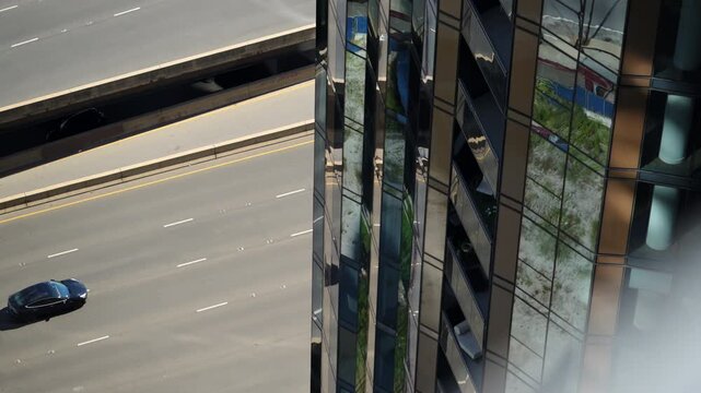 Aerial view of the busy multilane highway traffic beside modern glass skyscrapers, capturing fast-paced urban movement and city infrastructure. POV view