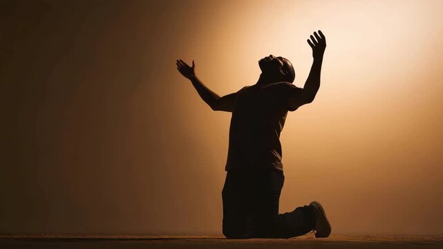 Man kneeling with raised hands, symbolizing faith, spirituality, hope, gratitude, and a deep personal connection with the divine.