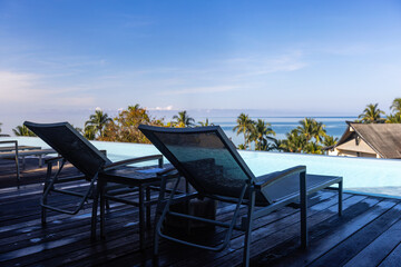 luxury rooftop swimming pool in beach hotel, two deck chairs near infinity pool