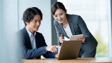 PC画面を指差して説明を受けるスーツ姿の男性