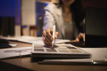 Close-up of an interior designer pointing at surface material swatches while choosing textures catalog for a design project at night