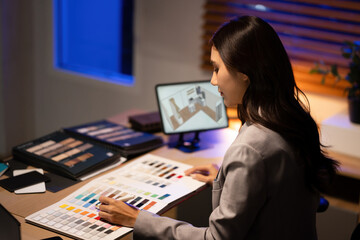 Asian woman interior designer selecting a color palette with samples while planning a digital 3D layout on tablet screen