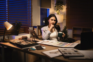 Designer taking a thoughtful break with coffee, focusing on creative decisions and material choices at her desk