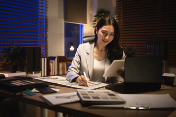 Professional designer selecting textures and finishes from a material guide in a cozy nighttime workspace