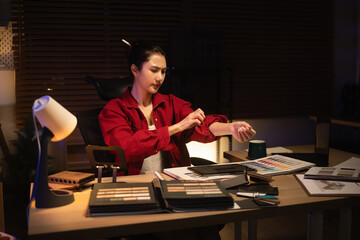 Determined interior designer ties her hair back and rolls up sleeves before continuing design work at night