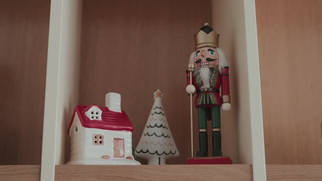Nutcracker figurine with small house and tree decoration on shelf