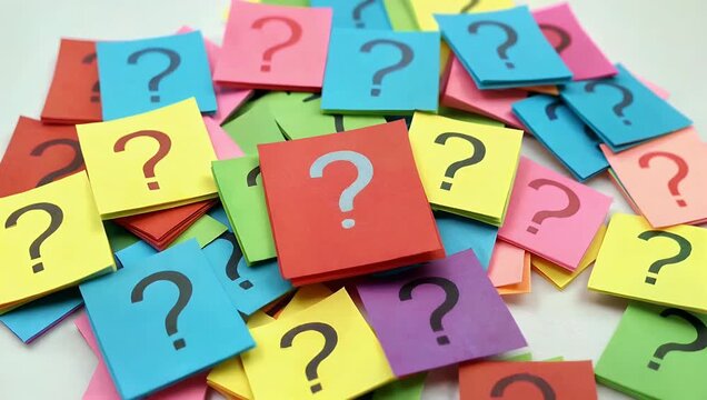 Close up 4K footage of pile of colorful paper notes covered question marks conveying curiosity inquiry brainstorming overwhelming questions educational office creative stock 