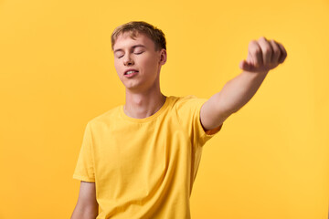 Fototapeta premium Youth relaxation stretching gesture with eyes closed against a yellow background, casual clothing, conveying calm energy and focus in a bright studio setting