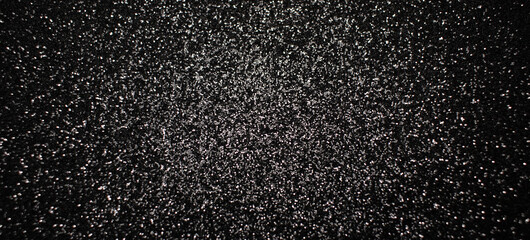 Black glitter texture background with silver sparkles, shimmering abstract surface