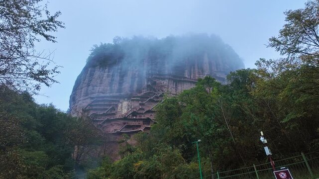 Maijishan Grottoes - Towering Cliff Carved With Steep Stairways Through Fog In Tianshui, China. low angle shot
