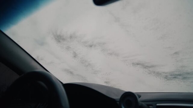 Soapy foam flowing down a car windshield during a wash at a self-service cleaning station