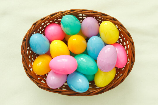 Top view of colorful Easter eggs in basket on a white surface