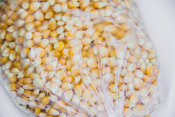 Macro closeup harvest yellow corn dry organic food, popcorn, ideal storage conditions, transparent container bag, raw material for corn oil manufacture, selective focus, shallow depth of field, Cairo 