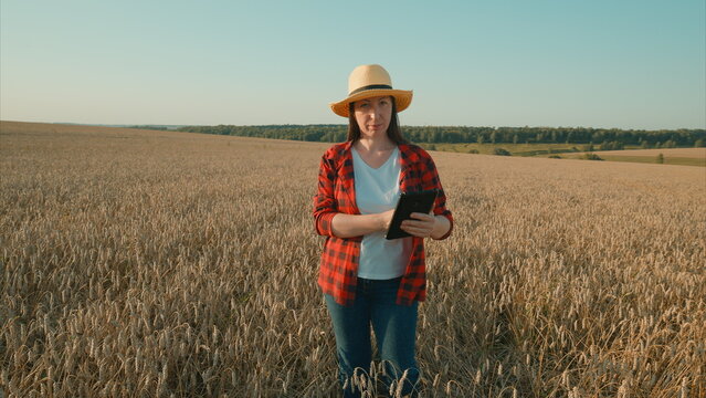 A woman in a field is using a tablet to engage with modern agriculture practices effectively - Powered by Adobe