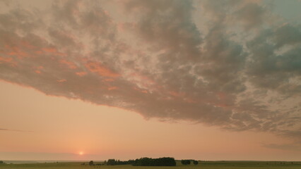 Time lapse. A Serene Sunset Casting Hues Over Lush Green Fields and Softly Whispering Clouds Above