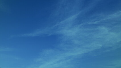 A peaceful scene featuring a serene blue sky adorned with soft, wispy clouds floating gently by