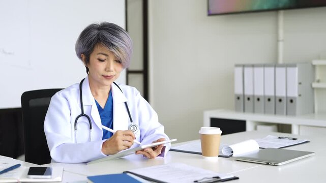 Doctor looking at laptop screen writing in notebook for research planning or medical tech innovation in hospital office. Healthcare medic worker, research strategy book notes and online communication.