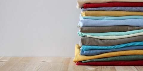 Stack of folded colorful clothes on light wooden table