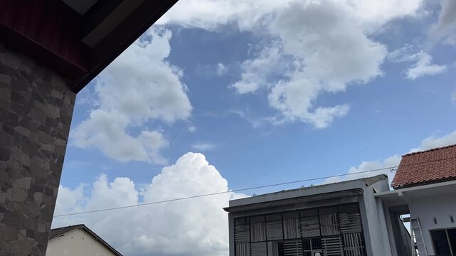 Time lapse Bright blue sky decorated with white cumulus clouds above a mix of modern and traditional residential buildings. Time-lapse clouds video