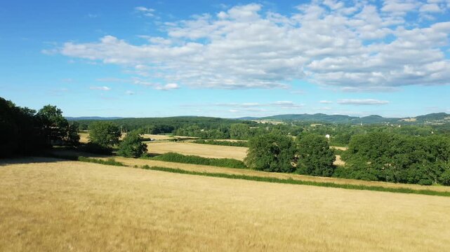 Scenic view of rolling fields and green trees under a blue sky in the Morvan countryside, France. Peaceful rural landscape with distant hills and scattered clouds.