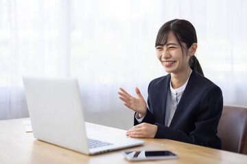 Asian Businesswoman Smiling in Online Meeting via Laptop