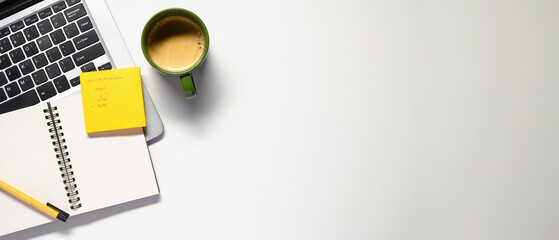 Office desk table with blank notebook, laptop, supplies and coffee cup. Top view with copy space. Flat lay.