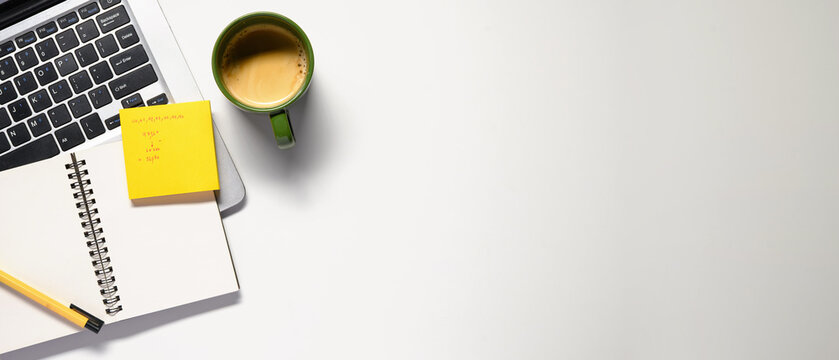 Office desk table with blank notebook, laptop, supplies and coffee cup. Top view with copy space. Flat lay.