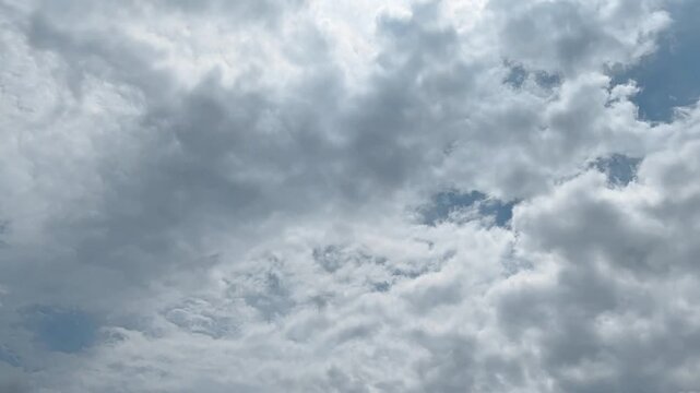Time lapse video footage of the sky dominated by fluffy white and grey clouds. Time-lapse clouds video