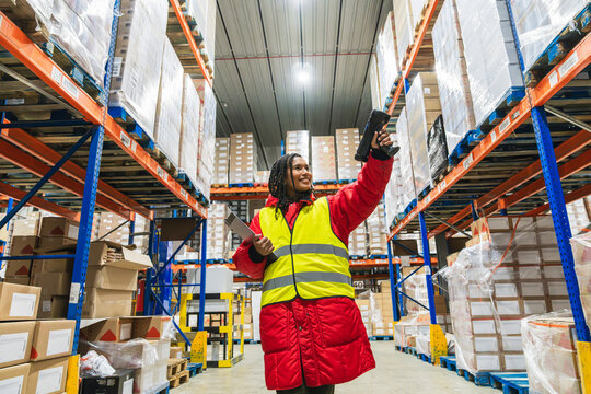 Woman wearing warm clothing scanning inventory with a barcode reader in a low temperature logistics warehouse - Powered by Adobe