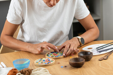 Woman creating decorative coasters in a relaxed home craft setup. Emphasizes precision, material control, and thoughtful artistic routine.
