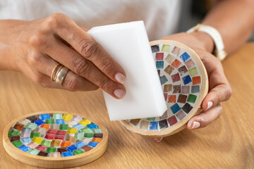 Making coasters at home, applying a final protective coat to coaster's surface during craft work. Highlights precision, coating control, and structured artistic finishing.