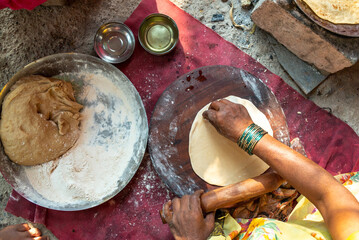 A close-up shot of a traditional Indian chapati being cooked on a clay stove and griddle in a rural village kitchen. This image represents authentic Indian culture, rural happy lifestyle