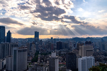Obraz premium Guiyang City Skyline at Dusk with Dramatic Cloud Rays and Mountain Vista