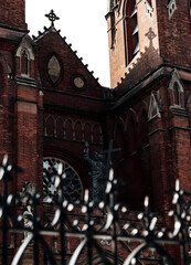 Obraz premium Gothic Cathedral with Stone Cross and Statue, Historic Brick Architecture